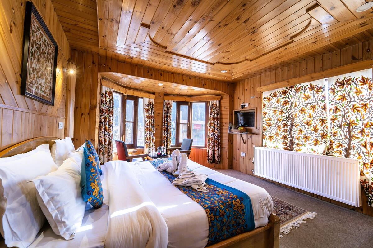A wooden cabin room with a bed, a table, and a TV.