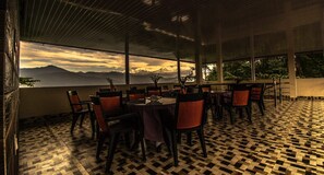 A restaurant with a checkered floor, tables with chairs, and a view of mountains. - MOUNTAIN MIST (Darjeeling)