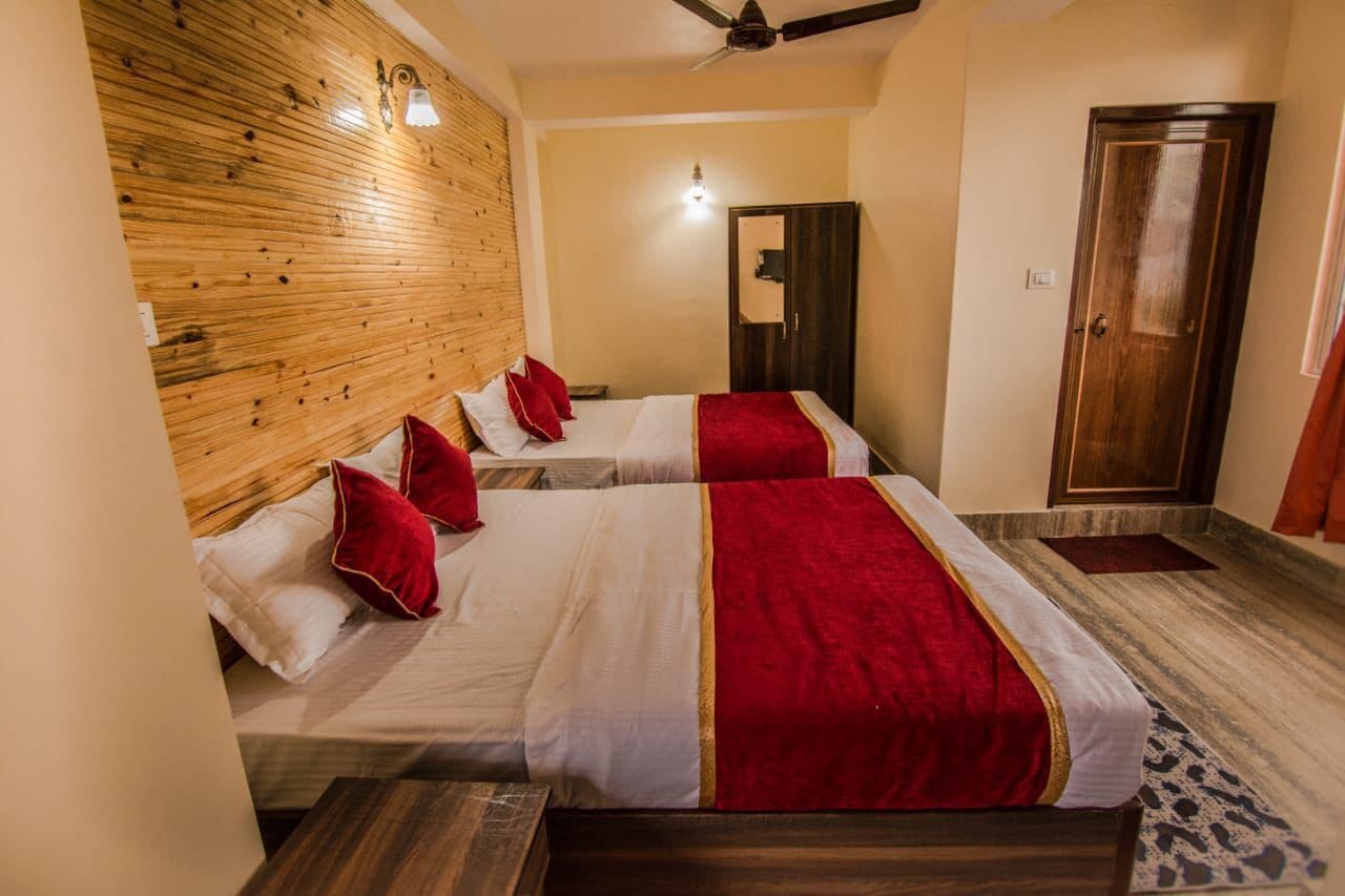 A hotel room with two beds, wooden headboard, a ceiling fan, and a wardrobe.