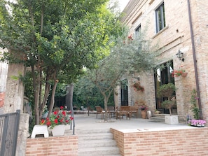 A courtyard with a brick wall, outdoor seating, and potted plants.