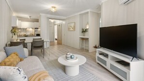 Ein modernes Wohnzimmer mit Flachbildfernseher, Essbereich und Küche.