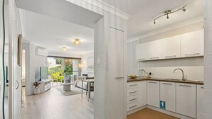 Eine moderne Küche mit weißen Schränken, einer Spüle und einem Essbereich mit Tisch und Stühlen.