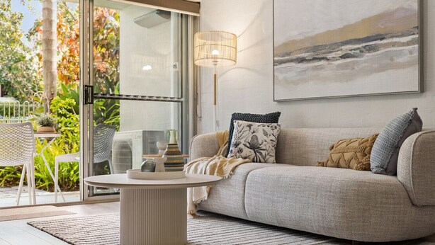 Ein modernes Wohnzimmer mit einer Couch, einem runden Couchtisch und einem Bild an der Wand.