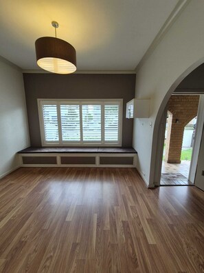 Ein Zimmer mit eingebautem Sitzplatz, einem großen Fenster und einer Tür, die nach draußen führt.