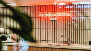 Eine Küche mit Mikrowelle, Spüle und einer Neonreklame an der Wand.