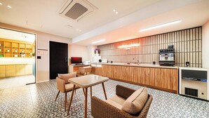 Eine Hotellobby mit Rezeption, Sitzgelegenheiten und einer Kaffeemaschine.