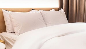 Ein Hotelzimmer mit einem hölzernen Kopfteil, weißer Bettwäsche und einem Nachttisch.