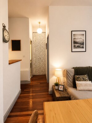 Ein gemütliches Wohnzimmer mit einem Holztisch, einer Couch, einer Lampe und einem gerahmten Bild an der Wand.