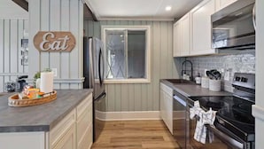 A kitchen with a refrigerator, stove, and cabinets.