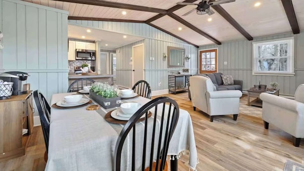 A spacious living area with a dining table, chairs, and a ceiling fan.