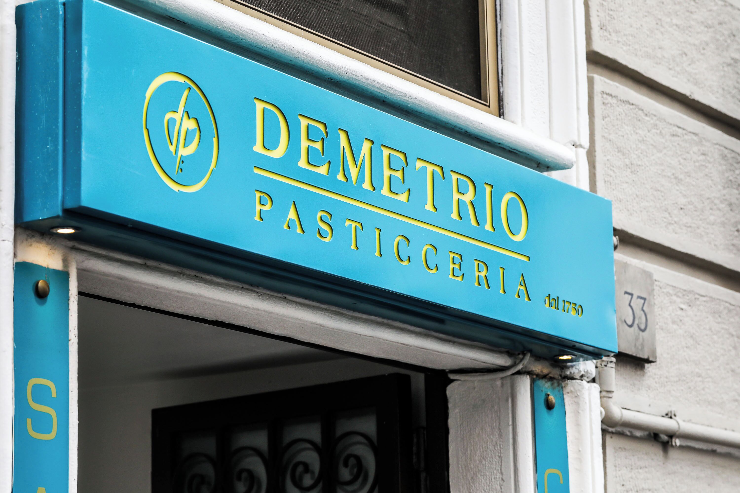 Una façana blava amb el nom 'DEMETRIO PASTICCERIA' i un logotip.