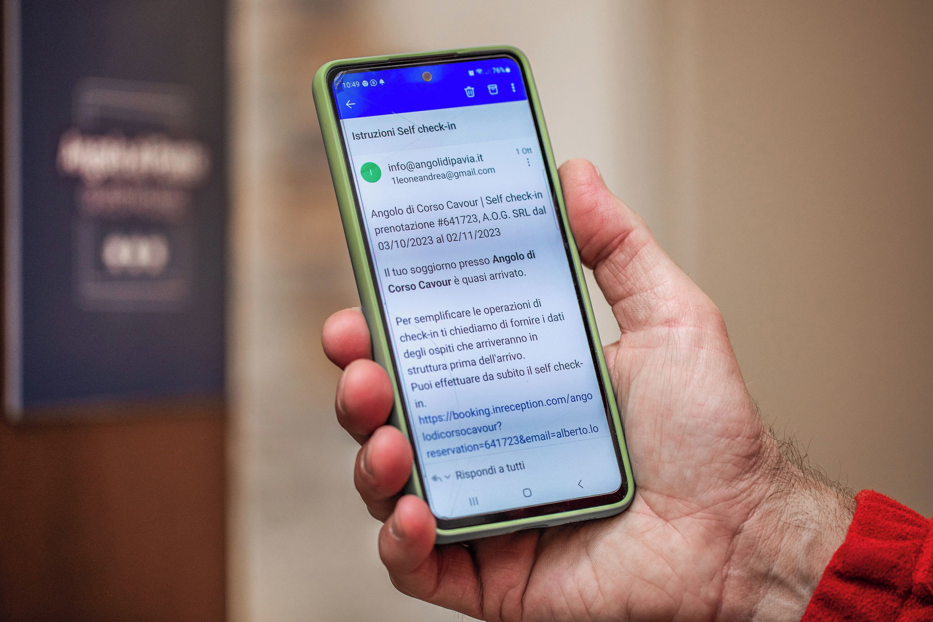 Una mano sosteniendo un teléfono inteligente que muestra un mensaje de registro automático para un hotel.