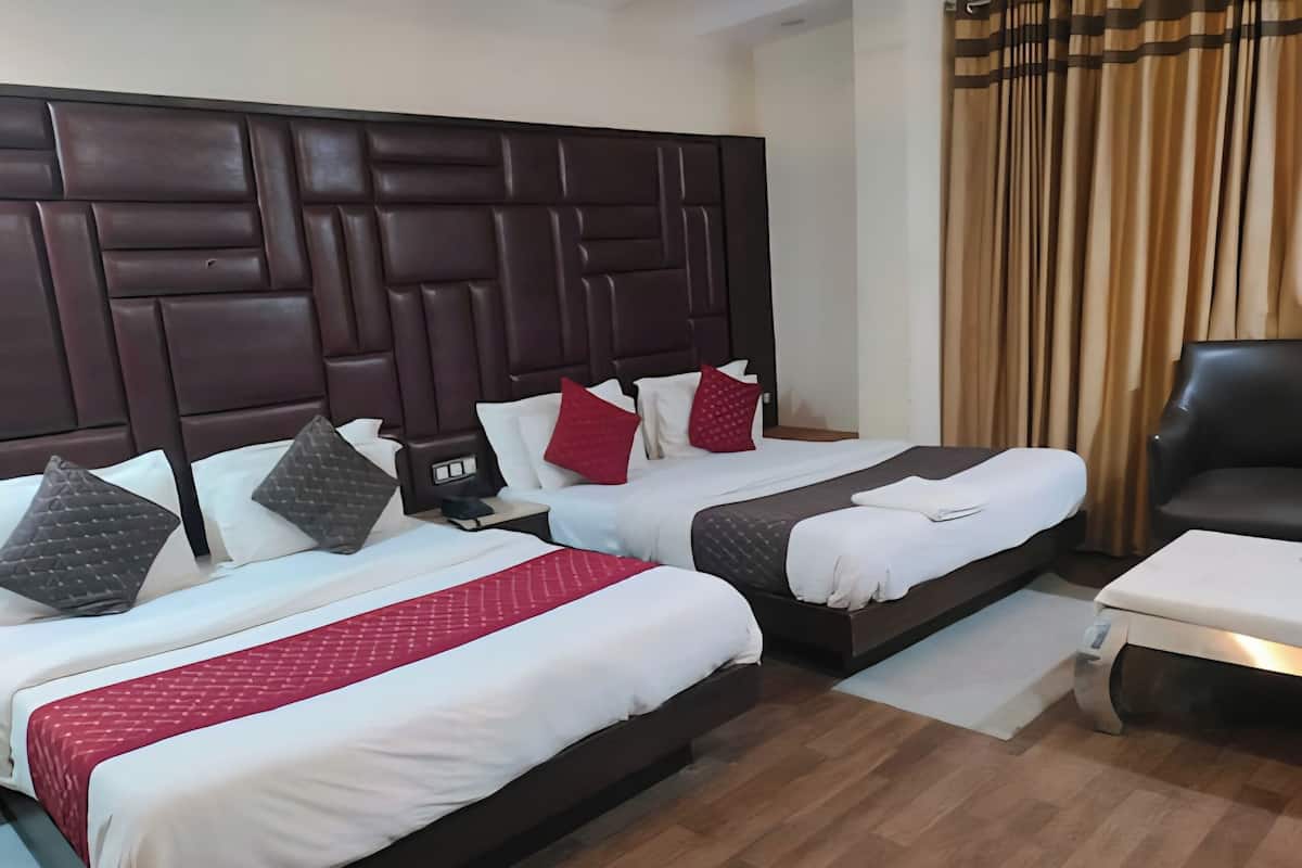 A hotel room with two beds, a dark headboard, a desk, and a chair.