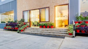A building with a brick facade, large glass doors, and a staircase leading to the entrance.
