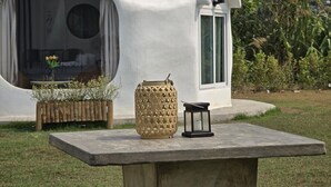 A modern, white, dome-shaped building with a circular window and a door. In front, there is a concrete table with a decorative lantern and a woven basket with plants. - FIELD GOOD Resort at Chiang Rai (Chiang Rai)