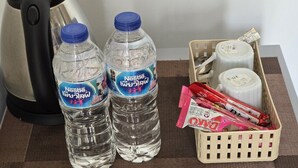Two Nestle water bottles, a kettle, and a basket with snacks and a thermos. - FIELD GOOD Resort at Chiang Rai (Chiang Rai)