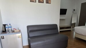 A compact living space with a sofa, a small refrigerator, and a television. - FIELD GOOD Resort at Chiang Rai (Chiang Rai)