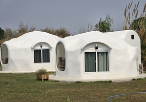 Two dome-shaped structures with arched windows and a small door, surrounded by grass and plants. - FIELD GOOD Resort at Chiang Rai (Chiang Rai)