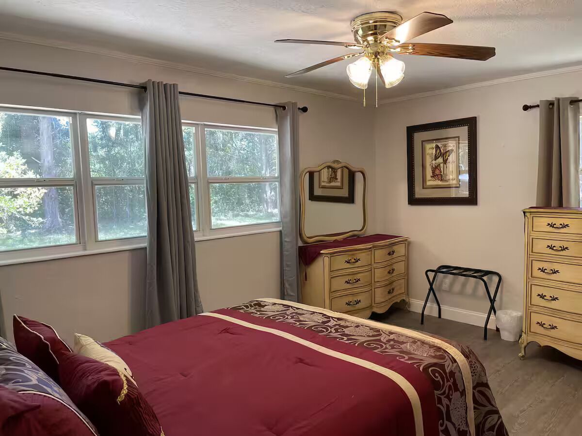 Ein Schlafzimmer mit Bett, Kommode, Spiegel und Deckenventilator.