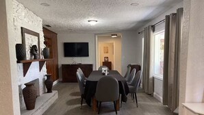 A dining area with a table, chairs, a television, and decorative vases.