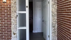 A doorway with a stone wall, a white door, and a brick wall.