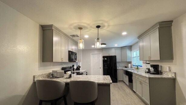 A modern kitchen with a central island, bar stools, and a refrigerator.