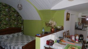 A bedroom with a bed, a table with various items, a chair, and a green wall. - Small pied-à-terre in the countryside (Causse-de-la-Selle)