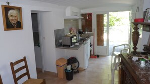 A kitchen with a microwave, toaster, and sink. There is a chair and a trash bin in the foreground. - Small pied-à-terre in the countryside (Causse-de-la-Selle)