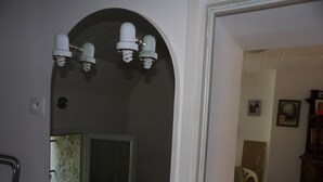 A bathroom with a white sink, mirror, and two light fixtures above the mirror. - Small pied-à-terre in the countryside (Causse-de-la-Selle)