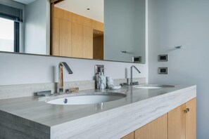 Ein modernes Badezimmer mit zwei Waschbecken, einem großen Spiegel und Holzschränken.