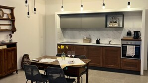 Una cocina moderna con comedor, que presenta una encimera de mármol, armarios de madera e iluminación colgante.