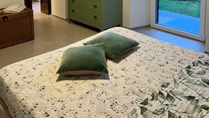 Un dormitorio con cama, cómoda, aire acondicionado de pared y vistas por una puerta de cristal.