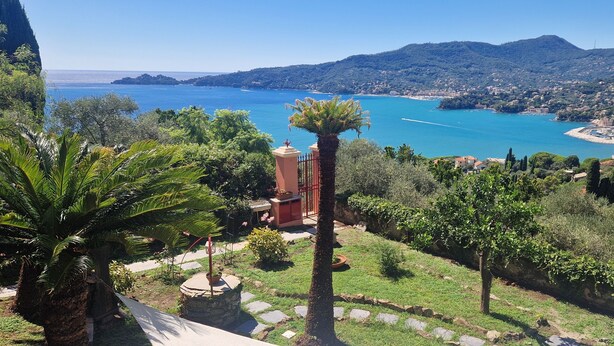 Paisaje costero con vista despejada al mar, un pequeño edificio de techo rojo y vegetación circundante.