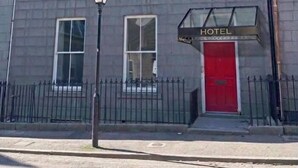 Un edificio de dos pisos con una puerta roja y un letrero que dice 'HOTEL'.
