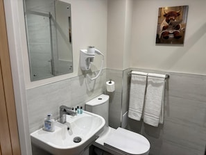 Un baño moderno con lavabo, inodoro y espejo.