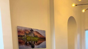 Un pasillo con un radiador, una alfombra escocesa y un cuadro de un castillo en la pared.