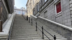 Unos escalones de piedra con barandillas negras que conducen a la entrada de un edificio.