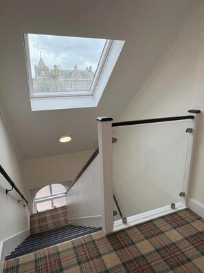 Una escalera con tragaluz que lleva a una vista de un edificio.