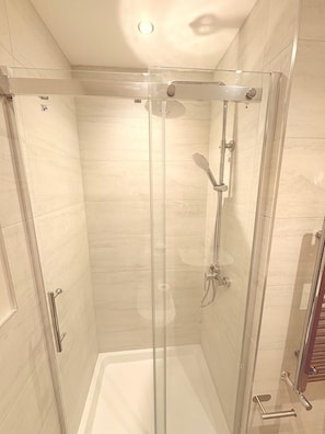 A glass-enclosed shower stall with a handheld showerhead and a wall-mounted faucet. - Super Nova Hotel (Aberdeen)