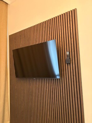 Un televisor de pantalla plana sujeto a un panel de madera a modo de revestimiento.