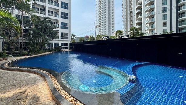 A swimming pool with a curved design, surrounded by a stone deck and pebbles. - Nam Talay by PSR (Nongprue)
