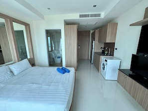 Une chambre d’hôtel moderne équipée d’un grand lit, d’un lave-linge, d’une télévision et d’une kitchenette.
