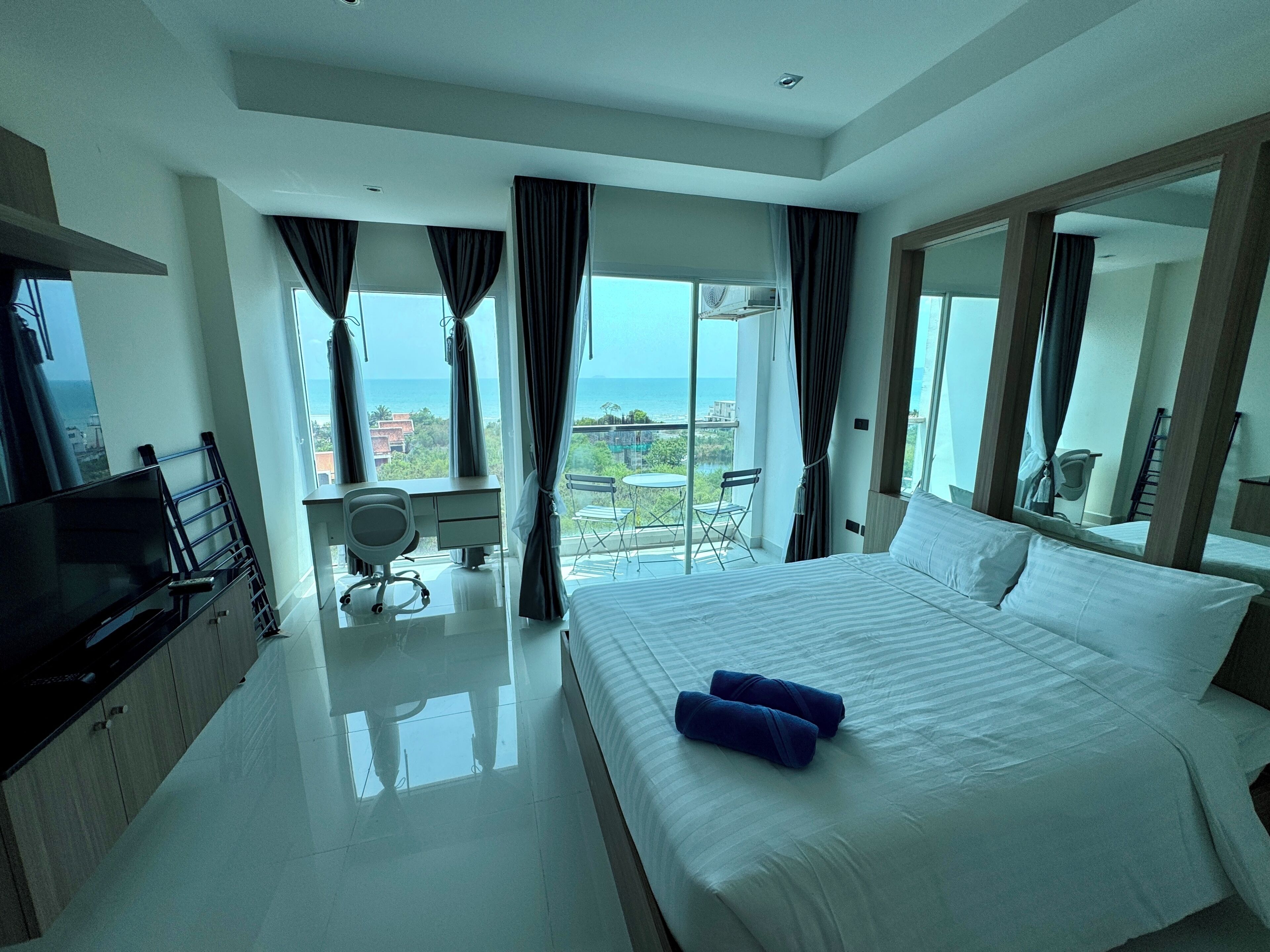 A modern hotel room with a large bed, a desk, a chair, and a television.