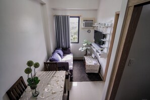 Ett kompakt bostadsutrymme med en soffa, ett matbord och en liten köksdel.