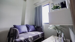 En moderne stue med sofa, et lille bord og en potteplante.
