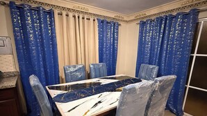 Ein Essbereich mit Tisch, Stühlen und blauen Vorhängen.