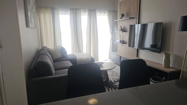Un salon moderne avec un canapé, une table basse et un téléviseur fixé au mur.