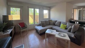 A living room with a sofa, a TV, a small table, and a window. - Villa du Cedre | House & Garden, Montrabe (Montrabé)