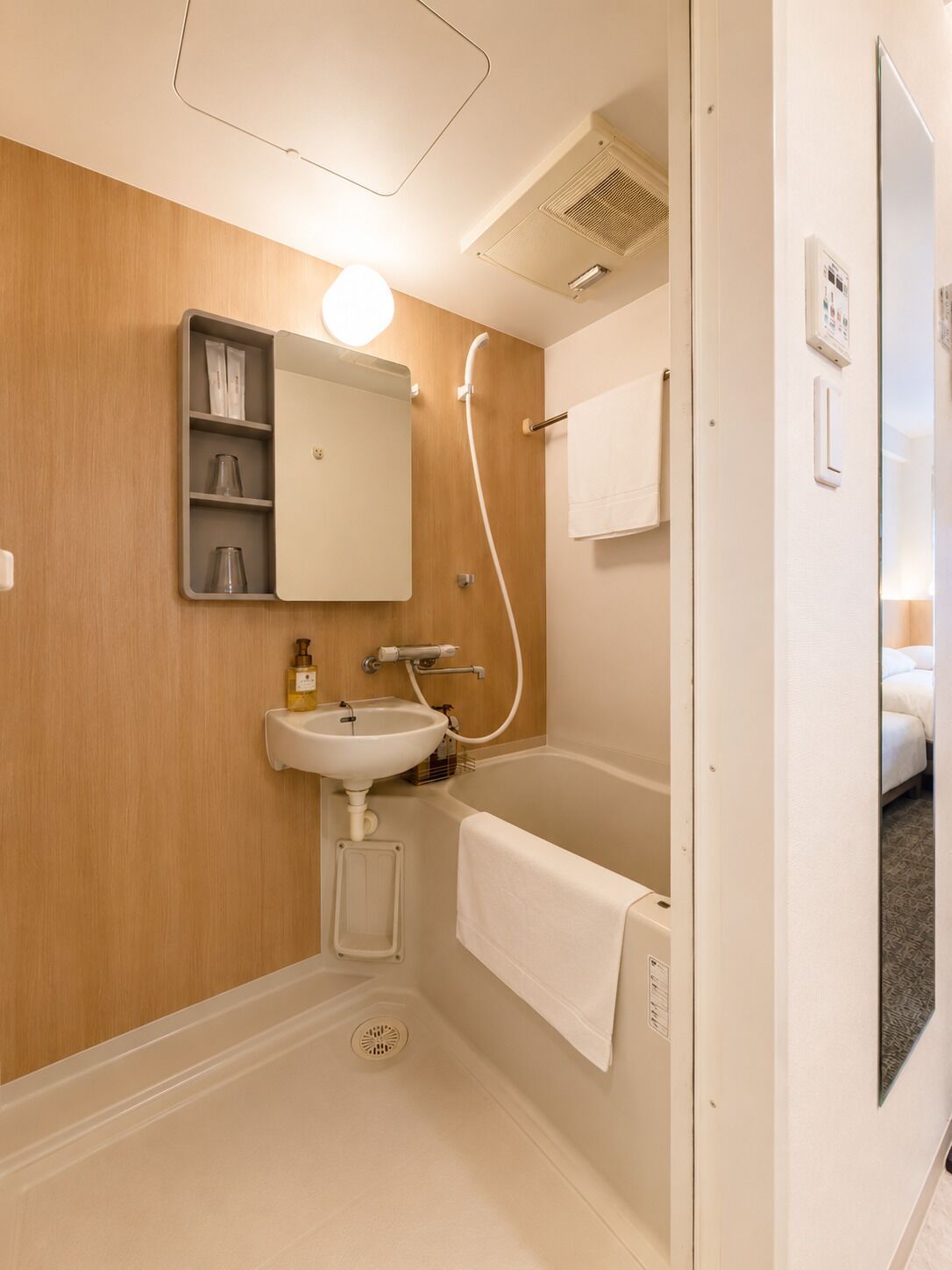 Een badkamer met een wastafel, spiegel, douche en handdoekhouder.