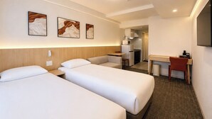Habitación de hotel con dos camas, un escritorio, una silla, un microondas y un televisor.